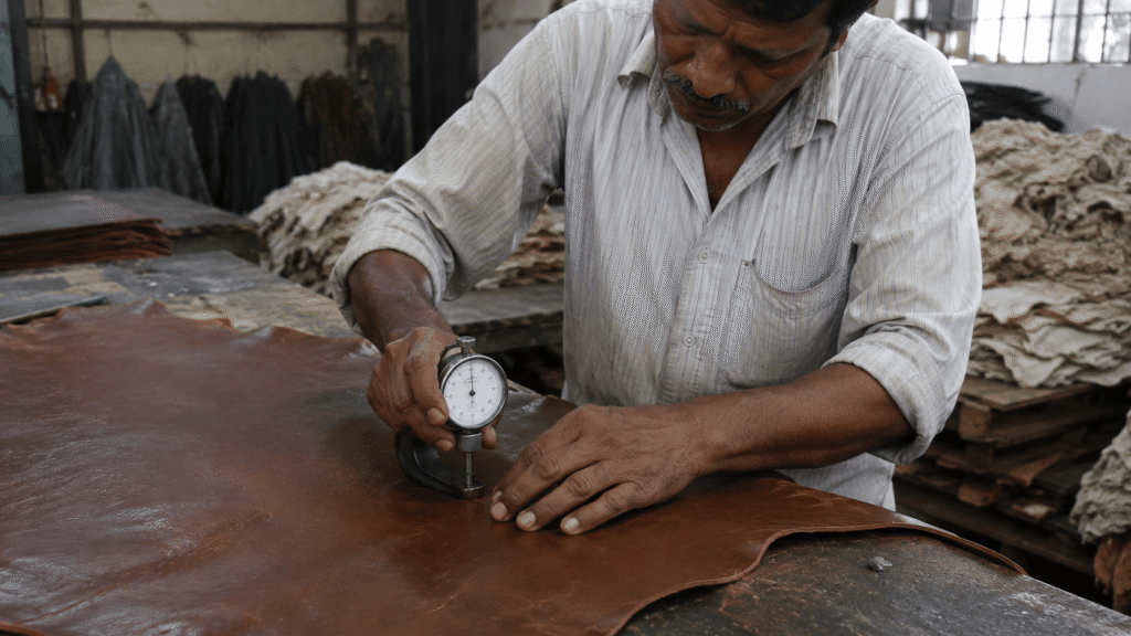 An artisan in SMPC Navsetu leather manufacturing facility measuring the thickness of leather